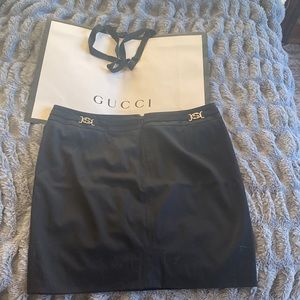 Black Gucci mini skirt with two silver GGs that rest on your back hips. With bag